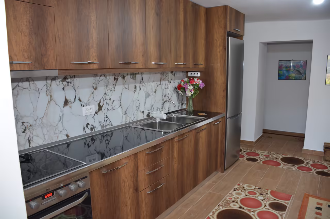 Kitchen with wooden cabinets, a hob, an oven and a refrigerator