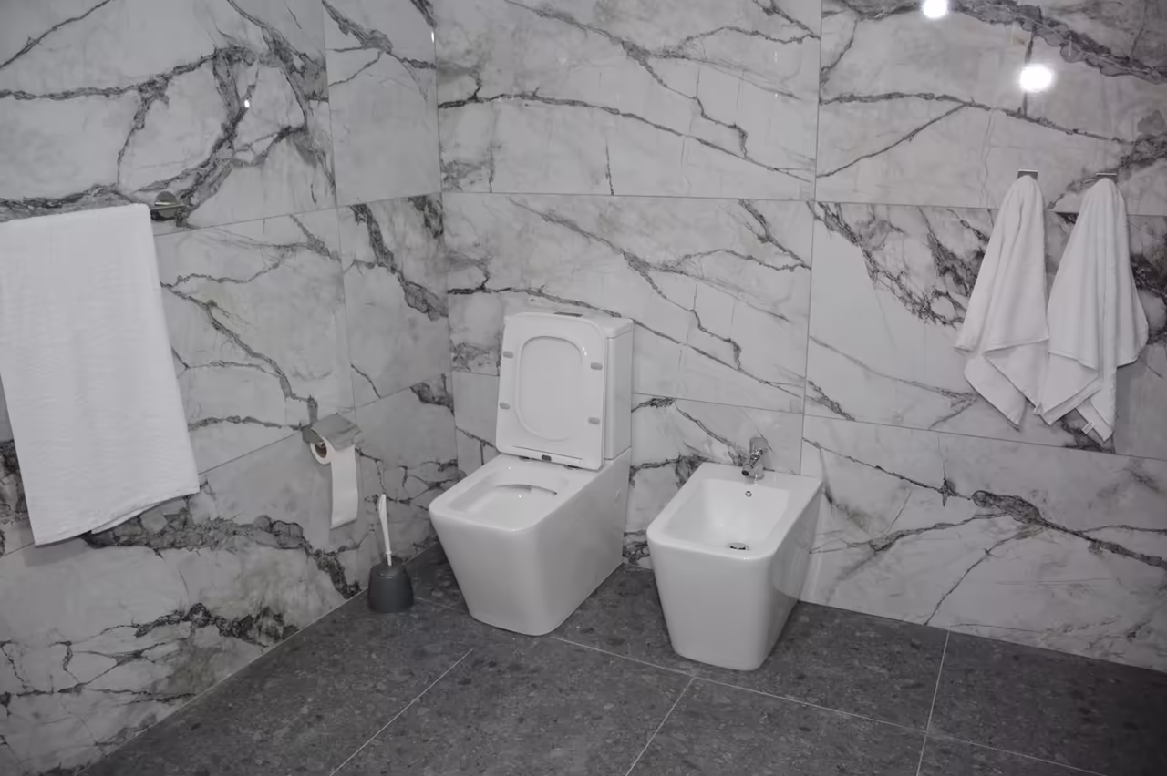 Bathroom with marble-look tiles, a toilet, a bidet and towels