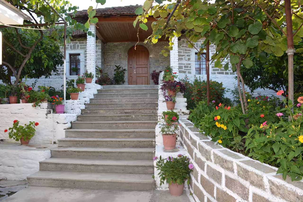 Garden steps with flower pots and a grapevine leading up to the stone house