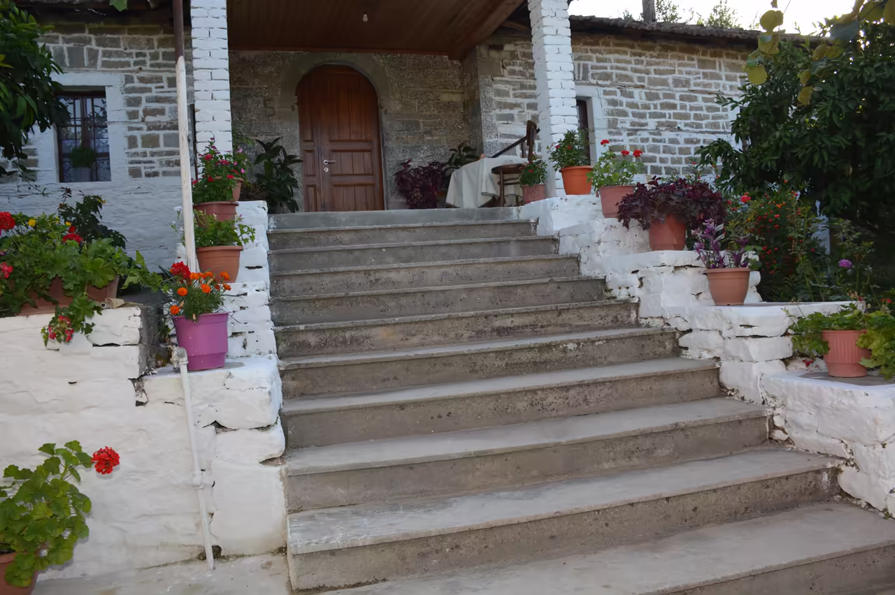Stone steps with flower pots leading to the arched wooden front door