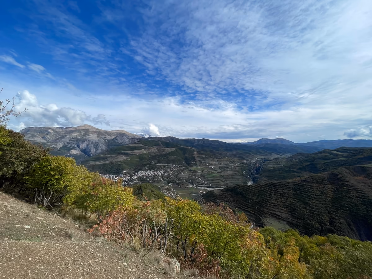 Wide ridge view with a village in the valley below, under a sky of small clouds