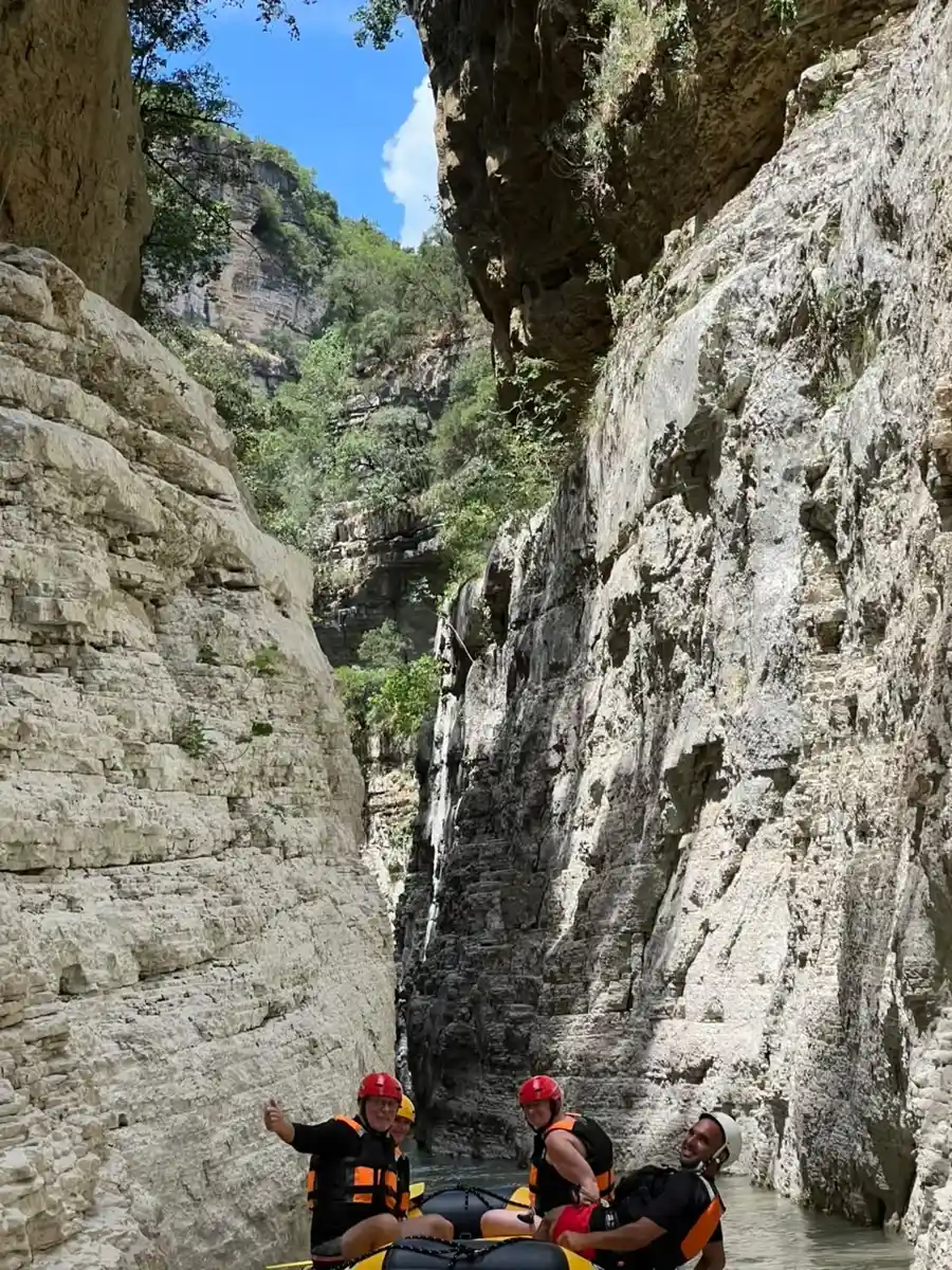 Vast canyon walls towering over a small rafting group in Osum Canyon