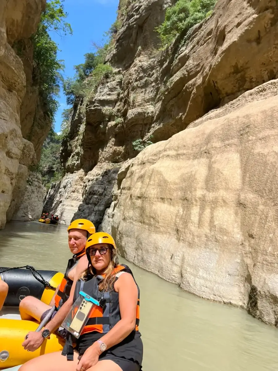 Couple rafting in yellow helmets, one wearing sunglasses