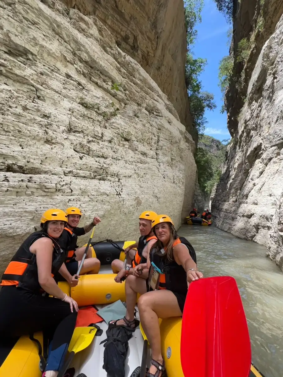 Four rafters with paddle raised in the narrow canyon corridor of the Osum River