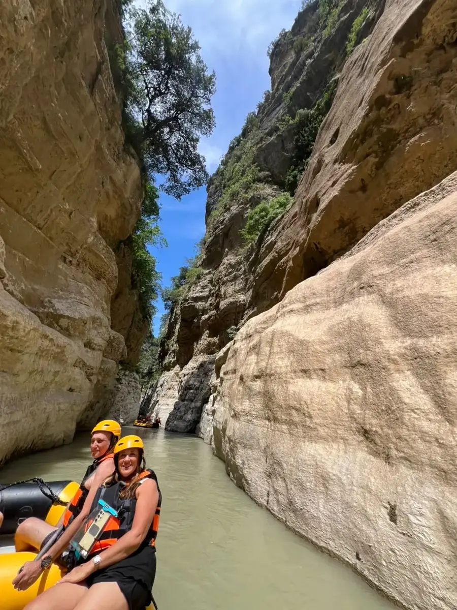 Raft with helmeted paddlers in a wide white-grey section of Osum Canyon