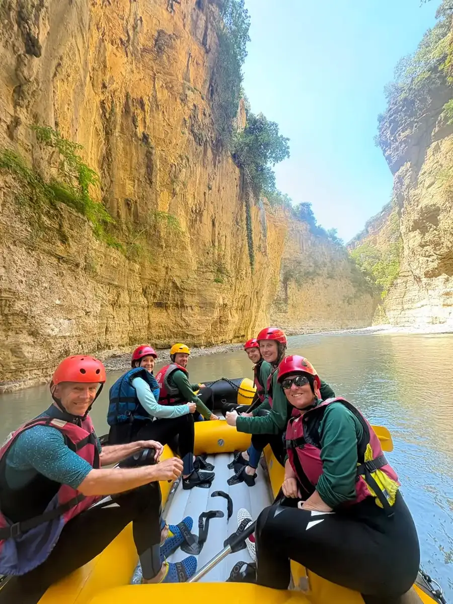 Rafters looking back at the camera as the raft drifts through a wide bend in Osum Canyon